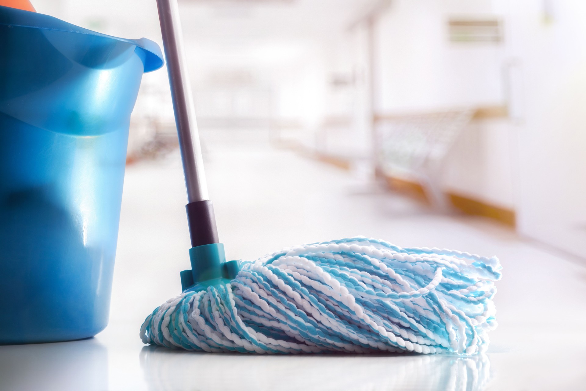 Mop and bucket on clean floor in a white corridor